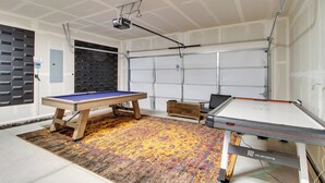 Ein Spielzimmer mit Billardtisch, Kicker und einem an der Decke befestigten Projektor.