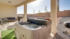 Ein überdachter Außenbereich mit Whirlpool, Grill und Sitzgelegenheit.