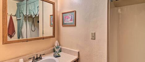 A bathroom with a large mirror, a sink, a towel rack, and a framed picture on the wall.