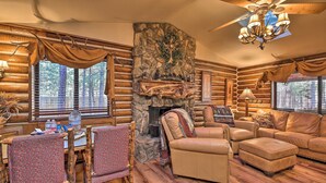 A log cabin interior with a stone fireplace, leather furniture, and a wooden dining table with chairs. - Family & Dog Friendly: Rustic Lakeside Cabin (Lakeside)