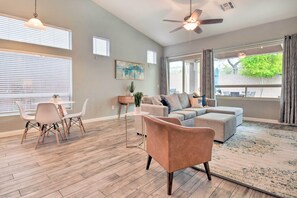 A spacious living room with a grey sofa, a coffee table, and a dining area with chairs and a small table. - Private Pool & Community Perks: Mesa Home! (Mesa)
