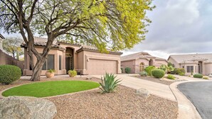 A residential area with houses featuring arched doorways, a well-maintained lawn, and a driveway leading to a garage. - Private Pool & Community Perks: Mesa Home! (Mesa)