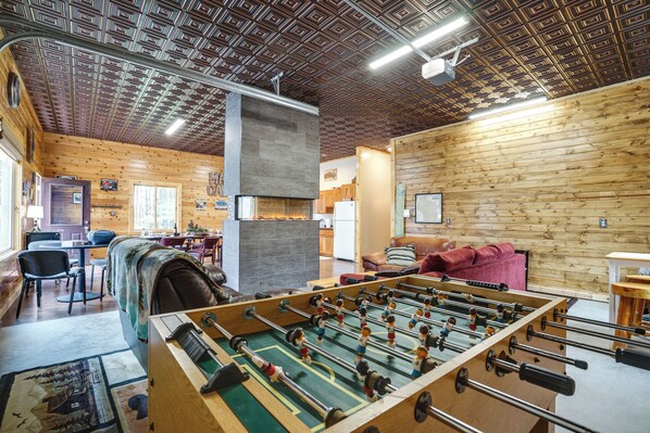 Un ambiente acogedor con una mesa de futbolín, paredes de madera y una chimenea.