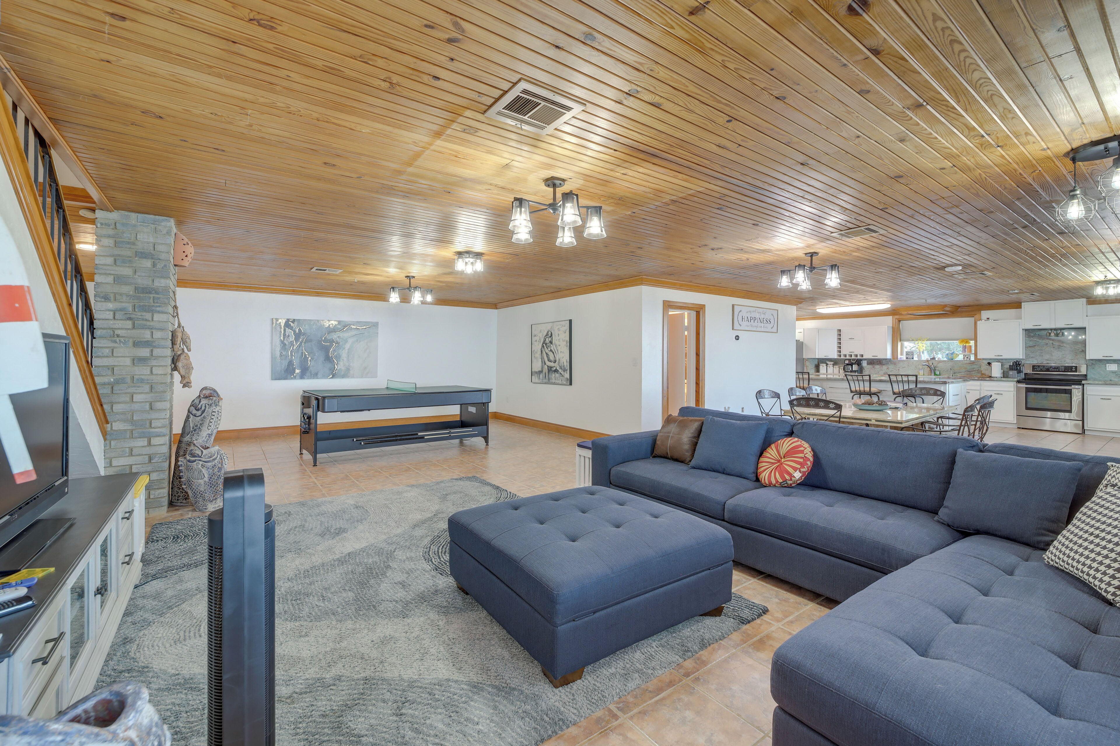 A modern living room with a sectional sofa, ottoman, and a flat-screen TV.
