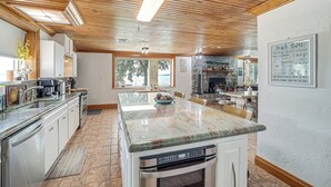 Een moderne keuken met een groot eiland, roestvrijstalen apparatuur en uitzicht op de eethoek.