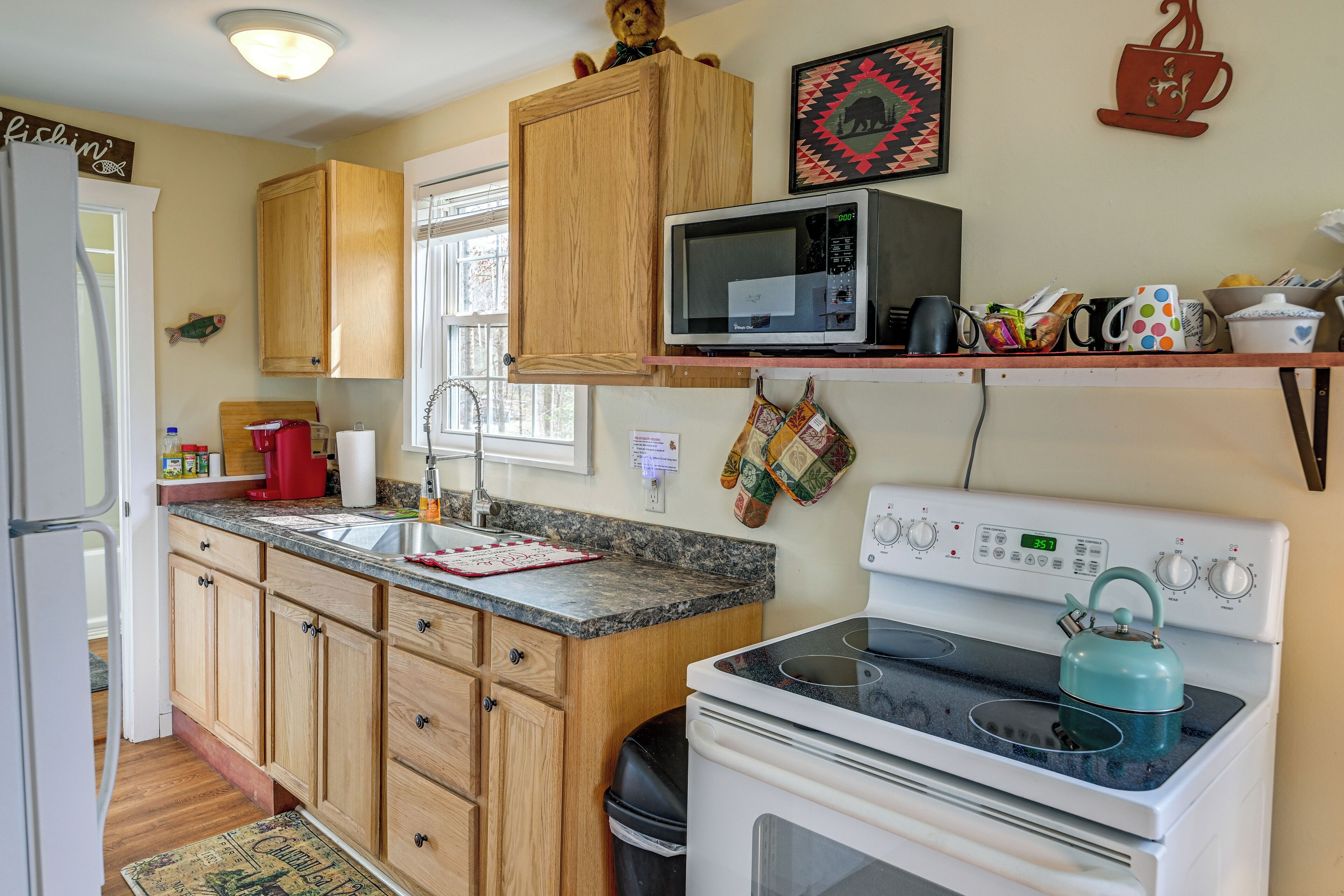 A kitchen with wooden cabinets, a microwave, a stove, and a coffee maker.