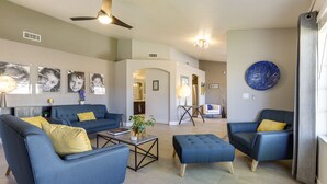A spacious living room with a ceiling fan, a blue sofa set, a coffee table, and a blue armchair. - Glendale Vacation Rental: Near State Farm Stadium (Glendale)