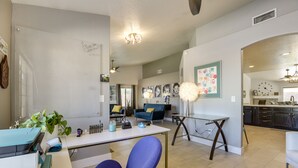 A modern living room with a whiteboard, a blue chair, a glass table, and a kitchen area in the background. - Glendale Vacation Rental: Near State Farm Stadium (Glendale)