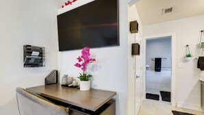 A modern office space with a desk, chair, and a large flat-screen TV mounted on the wall. - Glendale Vacation Rental: Near State Farm Stadium (Glendale)