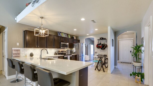 A modern kitchen with a central island, bar stools, dark cabinets, and stainless steel appliances. - Glendale Vacation Rental: Near State Farm Stadium (Glendale)