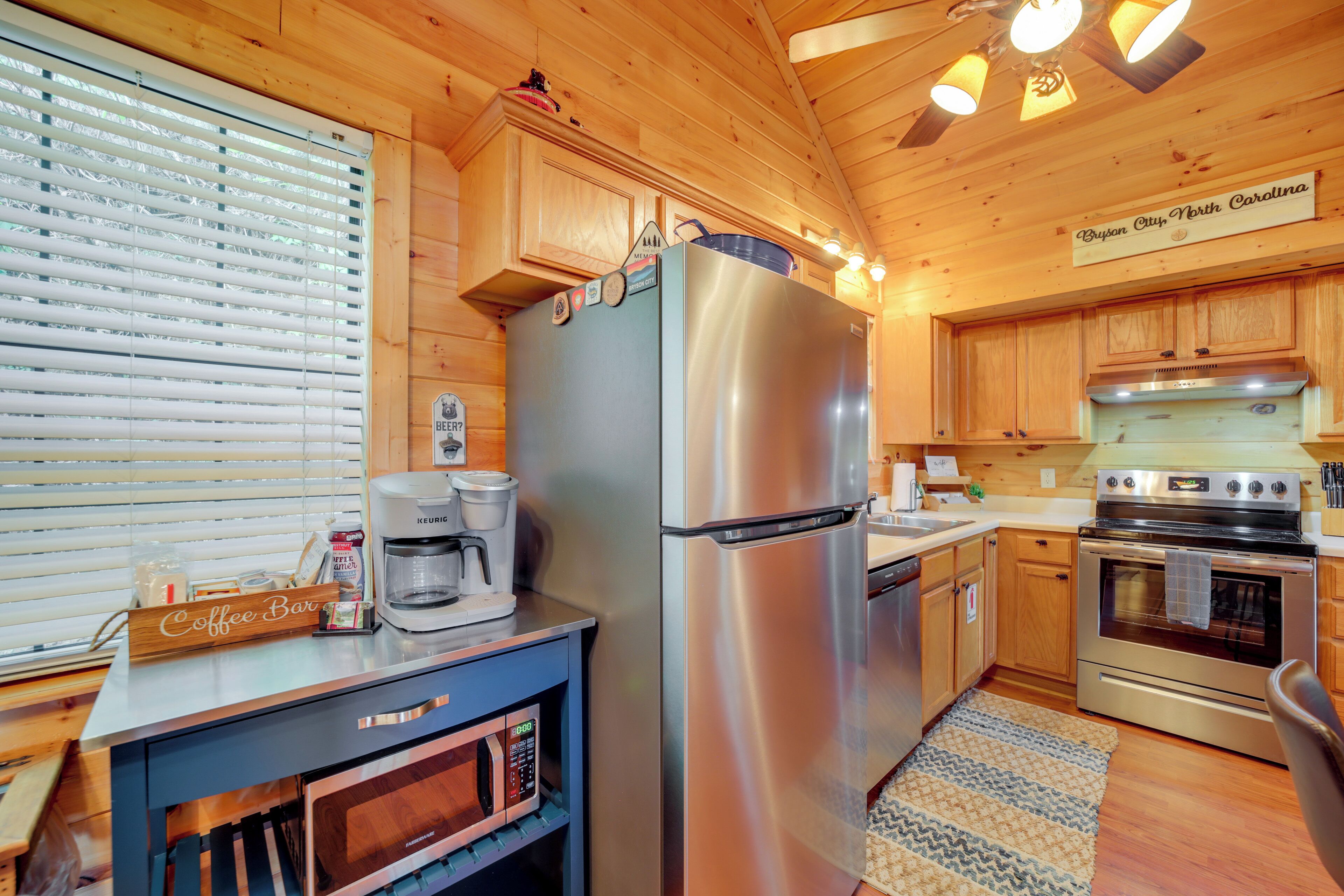 A modern kitchen with a stainless steel refrigerator, built-in microwave, and a coffee station.