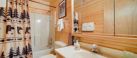 Une salle de bain rustique, aménagée dans une cabane en bois, avec des toilettes, un lavabo et une douche.
