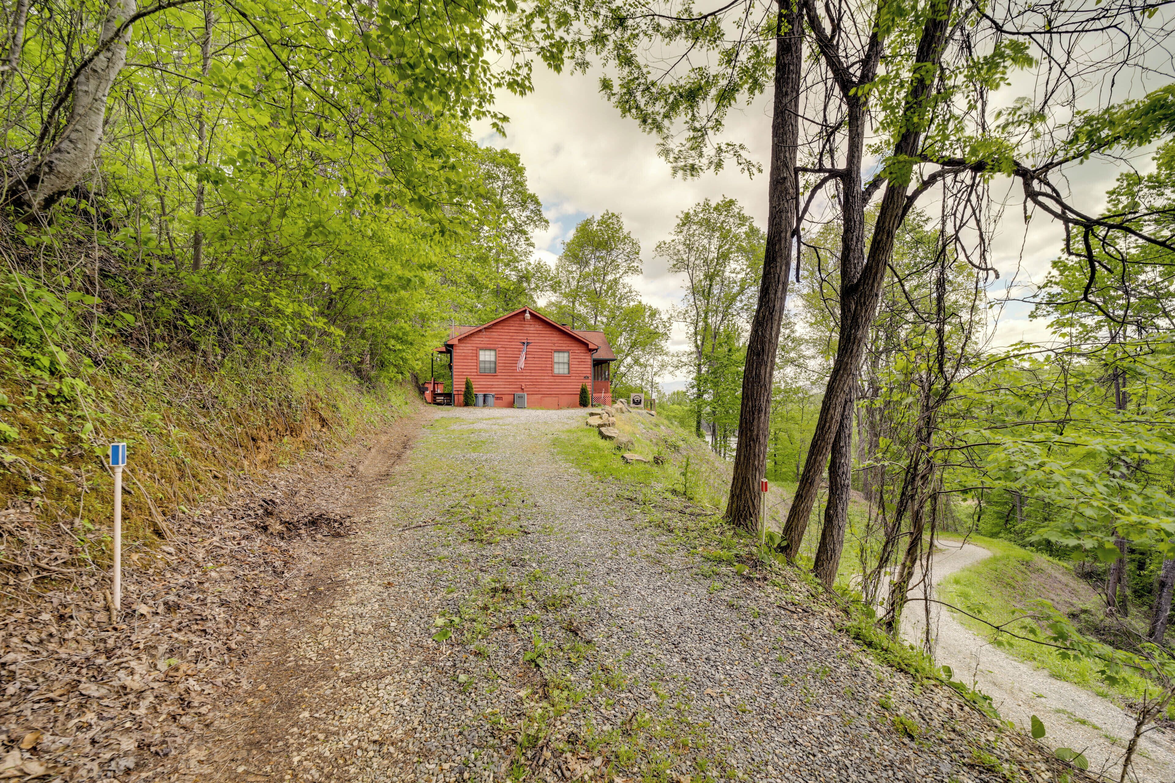 A gravel path leading to a red cabin surrounded by trees.