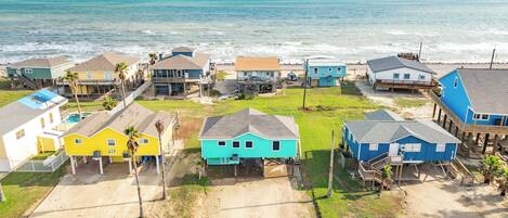 A coastal residential area with houses near the beach, featuring a mix of single and multi-story buildings, some with elevated structures.