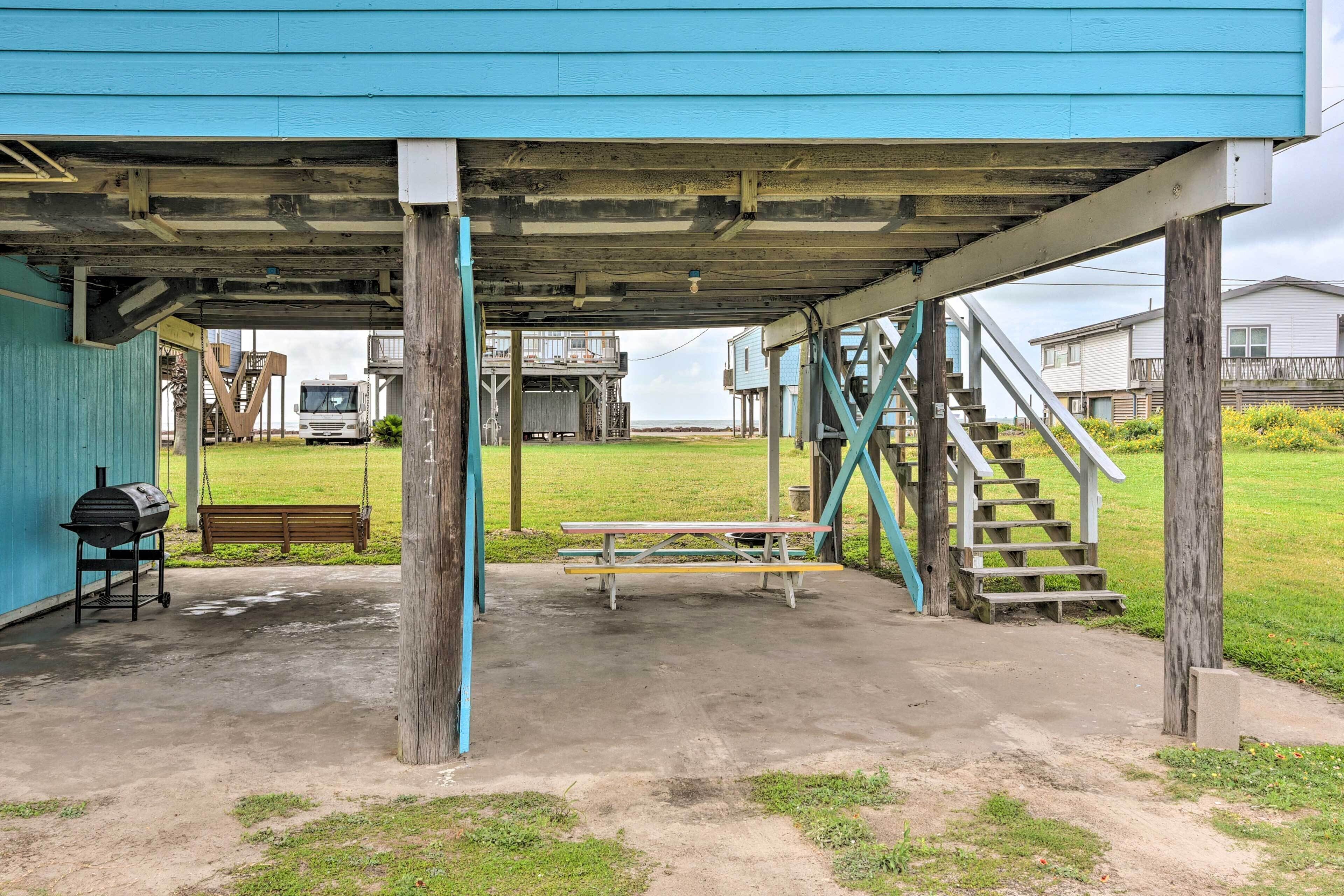Un espace extérieur abrité, doté d’un sol en béton, d’une table de pique-nique, d’un banc et d’un barbecue.