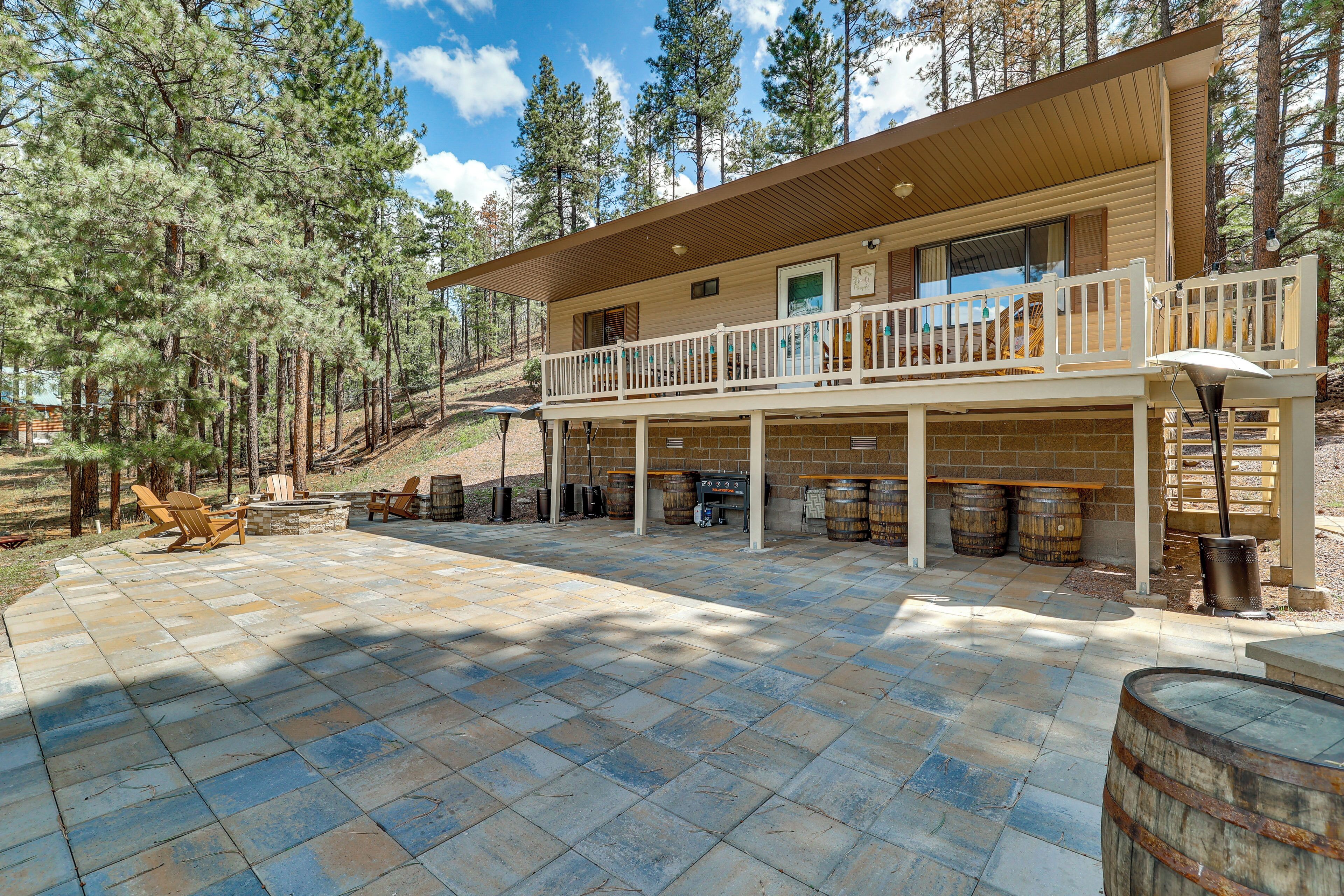 A two-story cabin with a balcony, stone patio, and outdoor seating area.