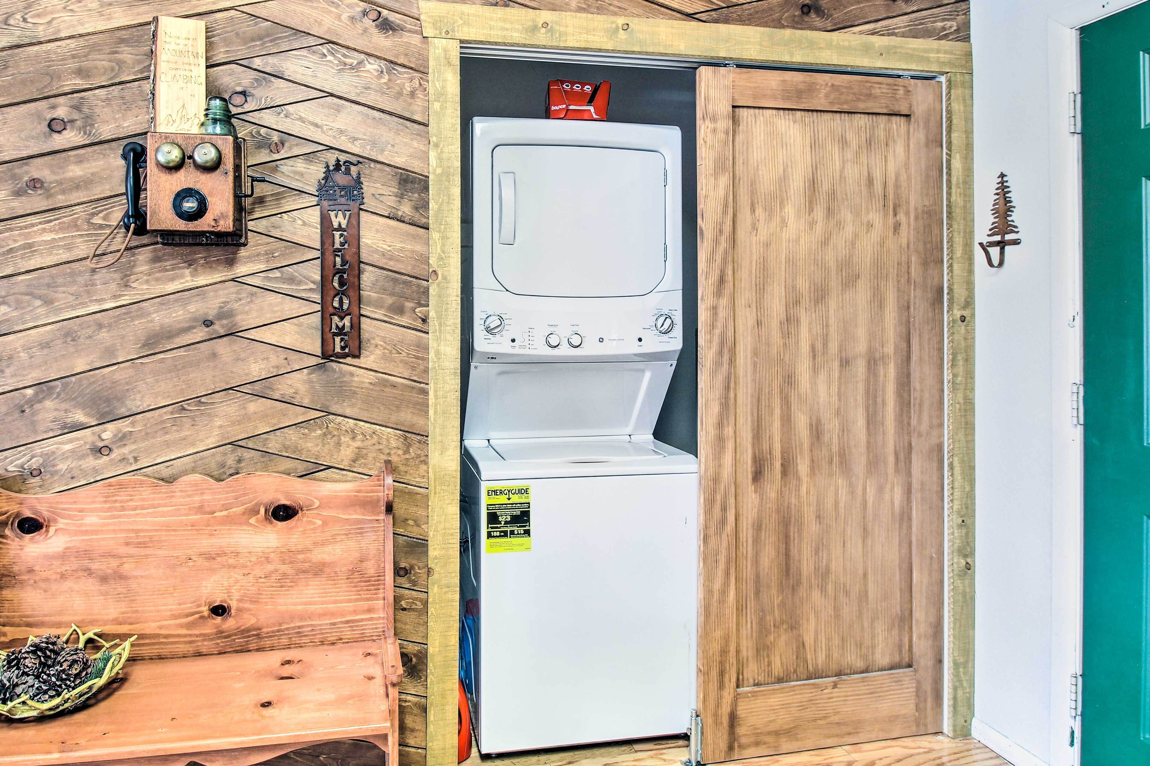 Un intérieur en bois avec un lave-linge blanc, un banc en bois et une porte sur laquelle est apposée une pancarte.