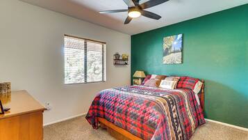 A bedroom with a bed, a ceiling fan, a window with blinds, and a green wall.