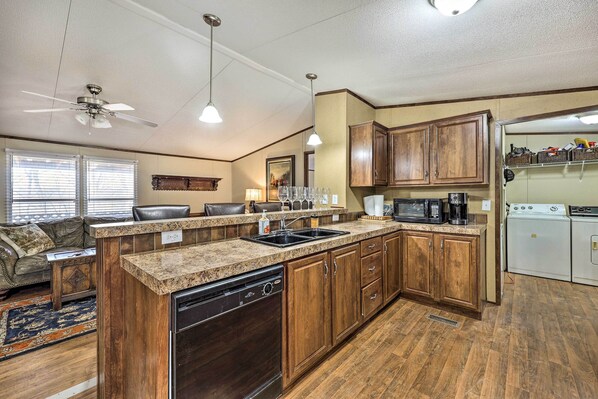 A kitchen with wooden cabinets, granite countertops, a dishwasher, a stove, and a ceiling fan. - 300-acre Mountain Retreat in the Arkansas Ozarks (Ozark)