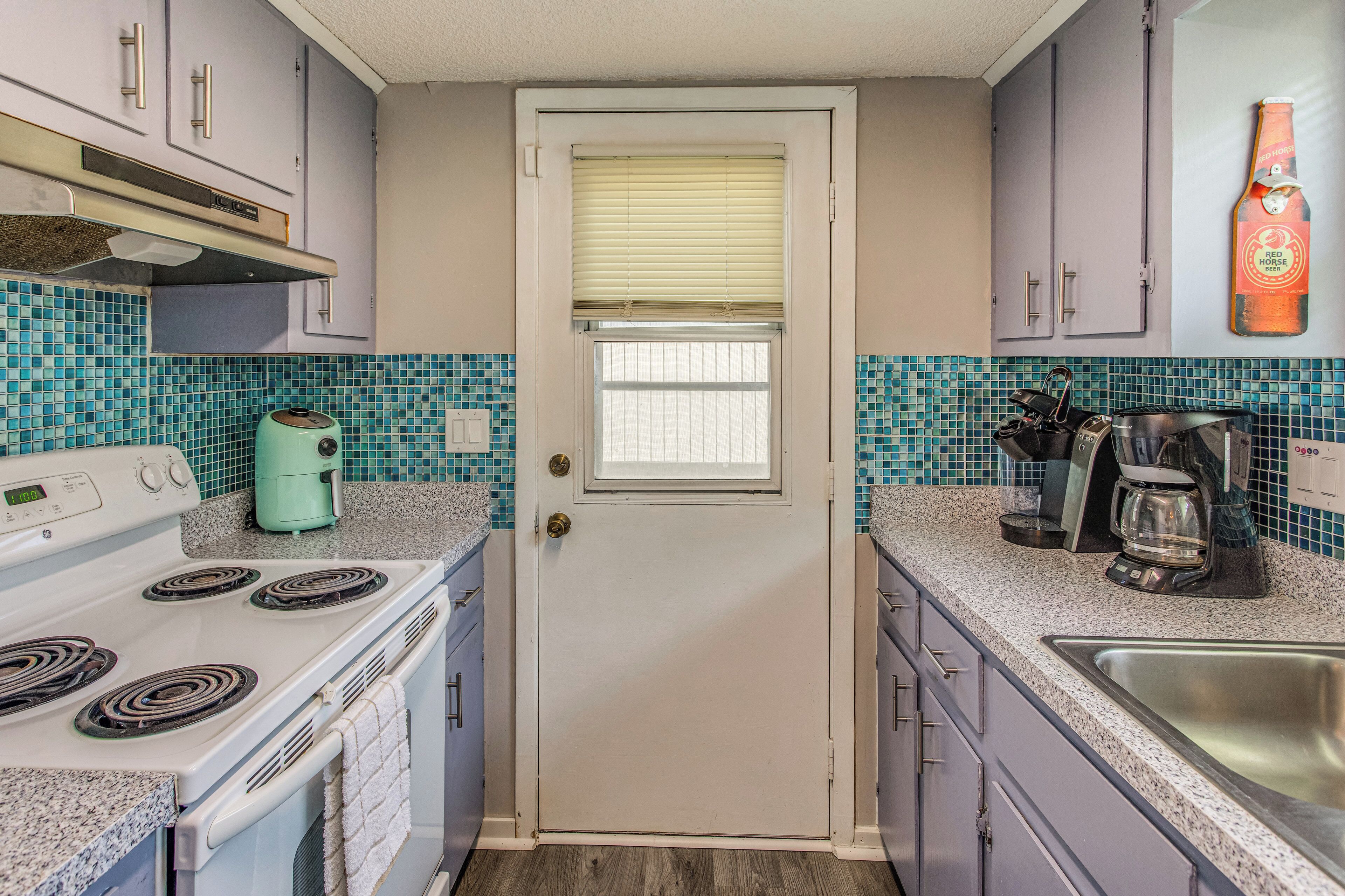 A kitchen with a white stove, a coffee maker, and a sink.