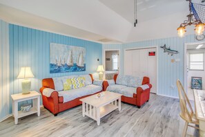 A living room with two red sofas, a white coffee table, and a painting of sailboats.