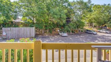 A parking area with cars, a wooden fence, and trees.