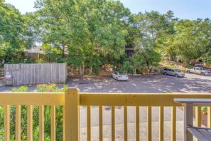 A parking area with cars, a wooden fence, and trees. - Myrtle Beach Cottage, Walk to Pools + Beach! (Myrtle Beach)