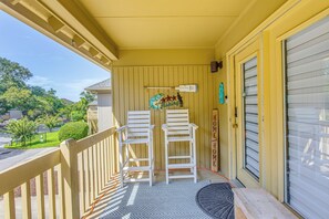 A porch with two white chairs, a small rug, and a decorative sign. - Myrtle Beach Cottage, Walk to Pools + Beach! (Myrtle Beach)