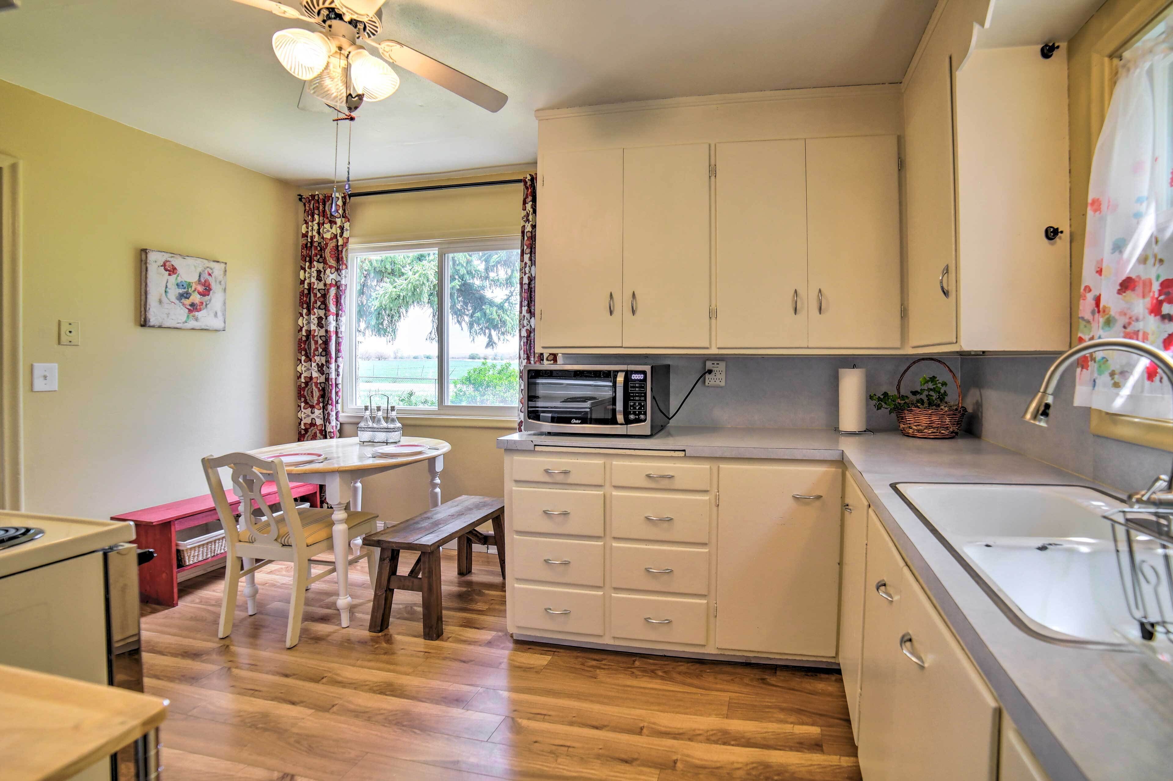 A compact kitchen with a microwave, sink, and wooden dining table.
