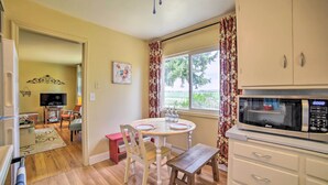 Une cuisine équipée d’un four à micro-ondes, une table à manger avec des chaises, un banc et une fenêtre avec des rideaux.