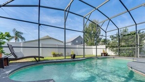 A swimming pool with a glass enclosure, surrounded by a white fence, and a lounge chair. - Backyard Oasis & Games: Davenport Magic Stay! (Davenport)