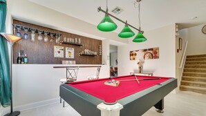 A pool table with a red felt surface, a bar area with glassware, and a staircase leading to another level. - Backyard Oasis & Games: Davenport Magic Stay! (Davenport)