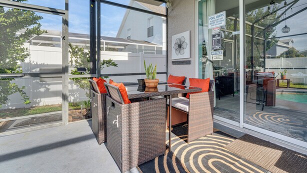 A glass-enclosed patio with wicker furniture, a glass table, and a potted plant. - Backyard Oasis & Games: Davenport Magic Stay! (Davenport)