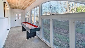 A pool table in a room with large windows and a wooden ceiling.