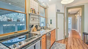 A modern kitchen with a large window, built-in shelves, and a stainless steel stove.
