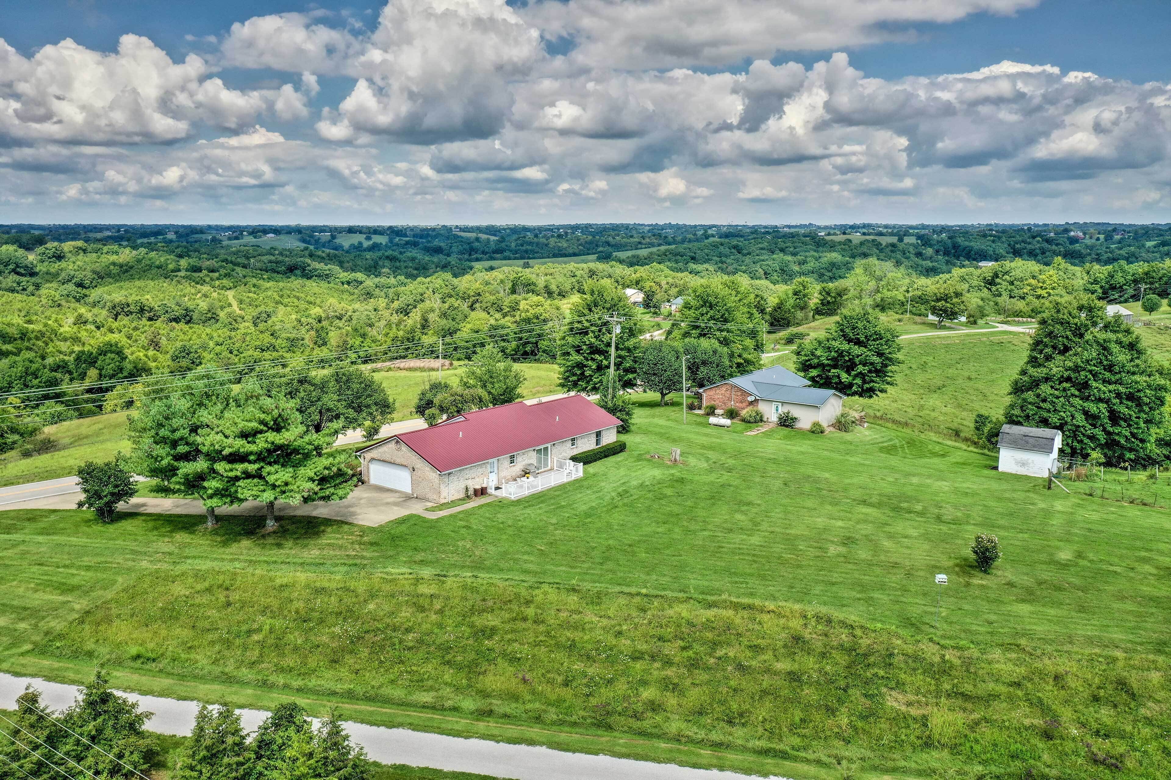 A rural property with a large house, a barn, and expansive green fields.