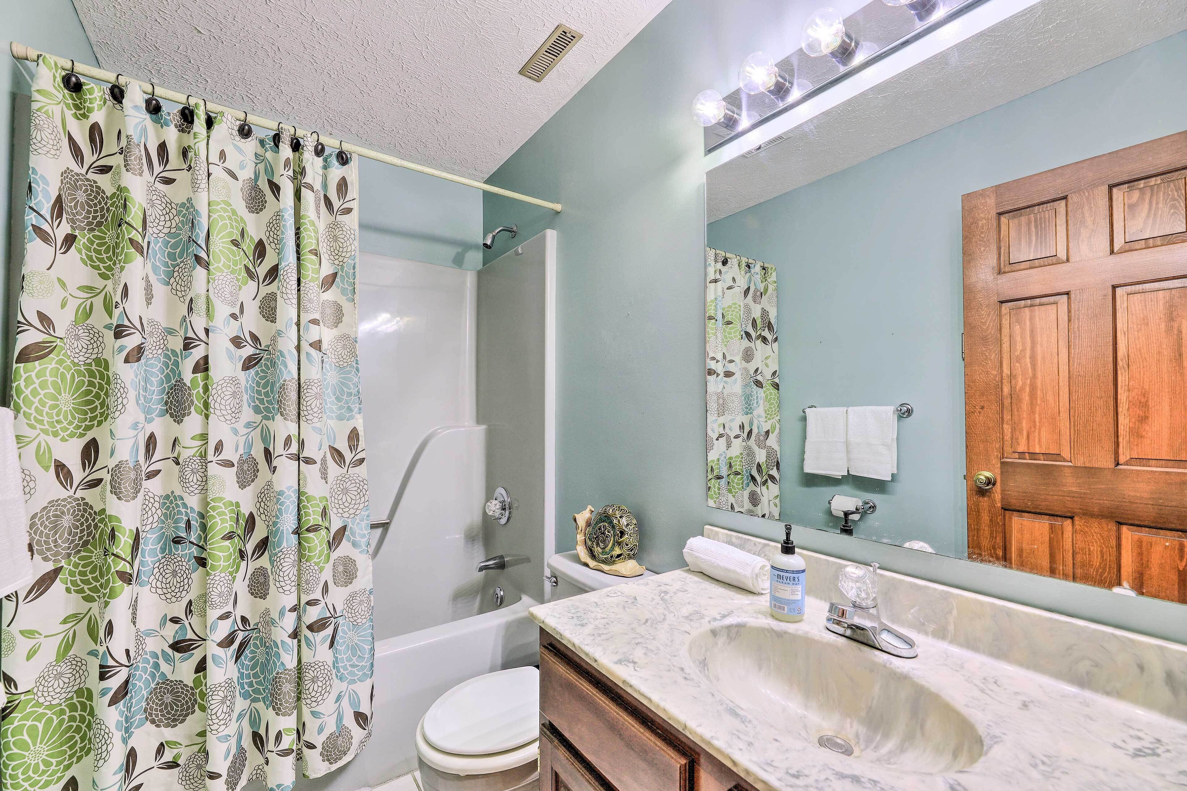 Een badkamer met douche, toilet, wastafel en een houten deur.