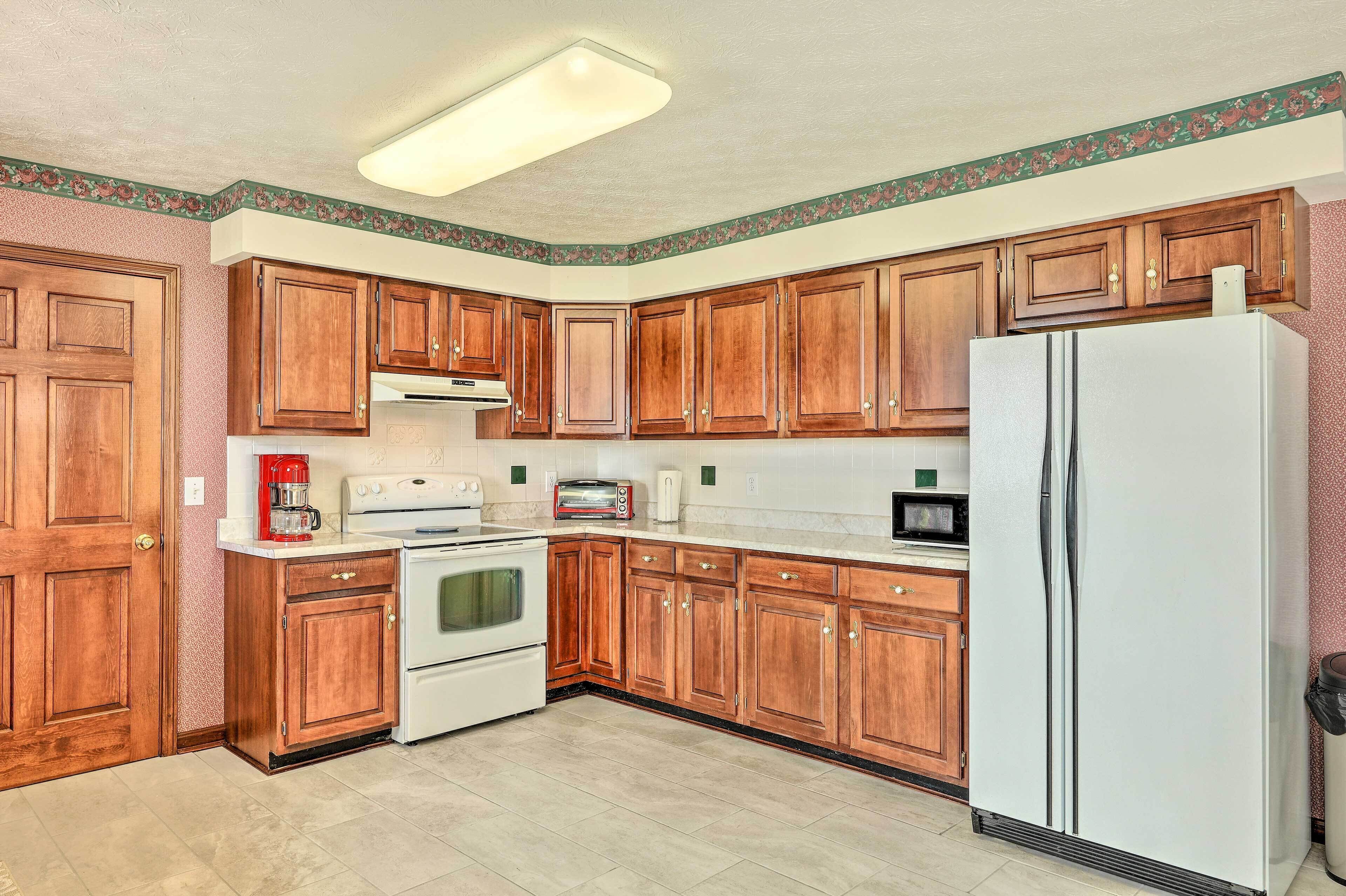 A kitchen with wooden cabinets, a white refrigerator, a stove, a microwave, and a toaster.
