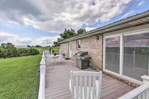 Un patio techado con una parrilla, asientos exteriores y vistas del paisaje circundante.