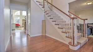 A spacious interior with a wooden staircase, a hallway leading to a room with a red chair, and a welcome sign.
