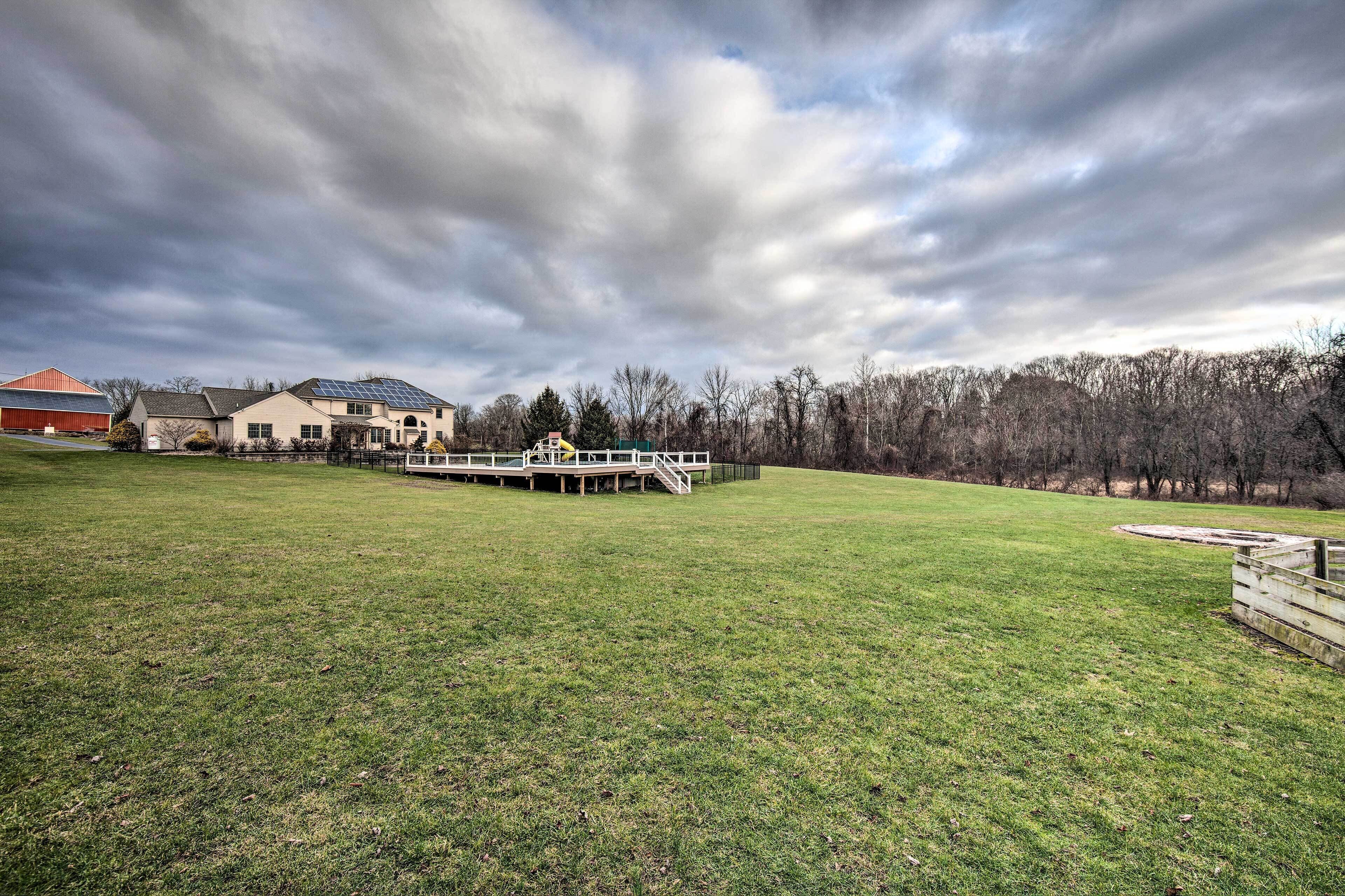 A large grassy field with a house and a deck.