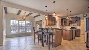 A spacious kitchen with a large island, bar stools, and pendant lighting.