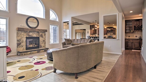 A spacious living room with a stone fireplace, a large sofa, and a wooden floor.