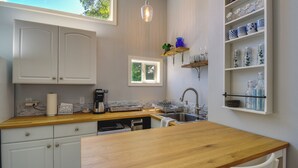 A kitchen with white cabinets, a wooden countertop, a sink, and a window. - Waterfront Hood Canal Cottage: Steps to the Beach! (Belfair)