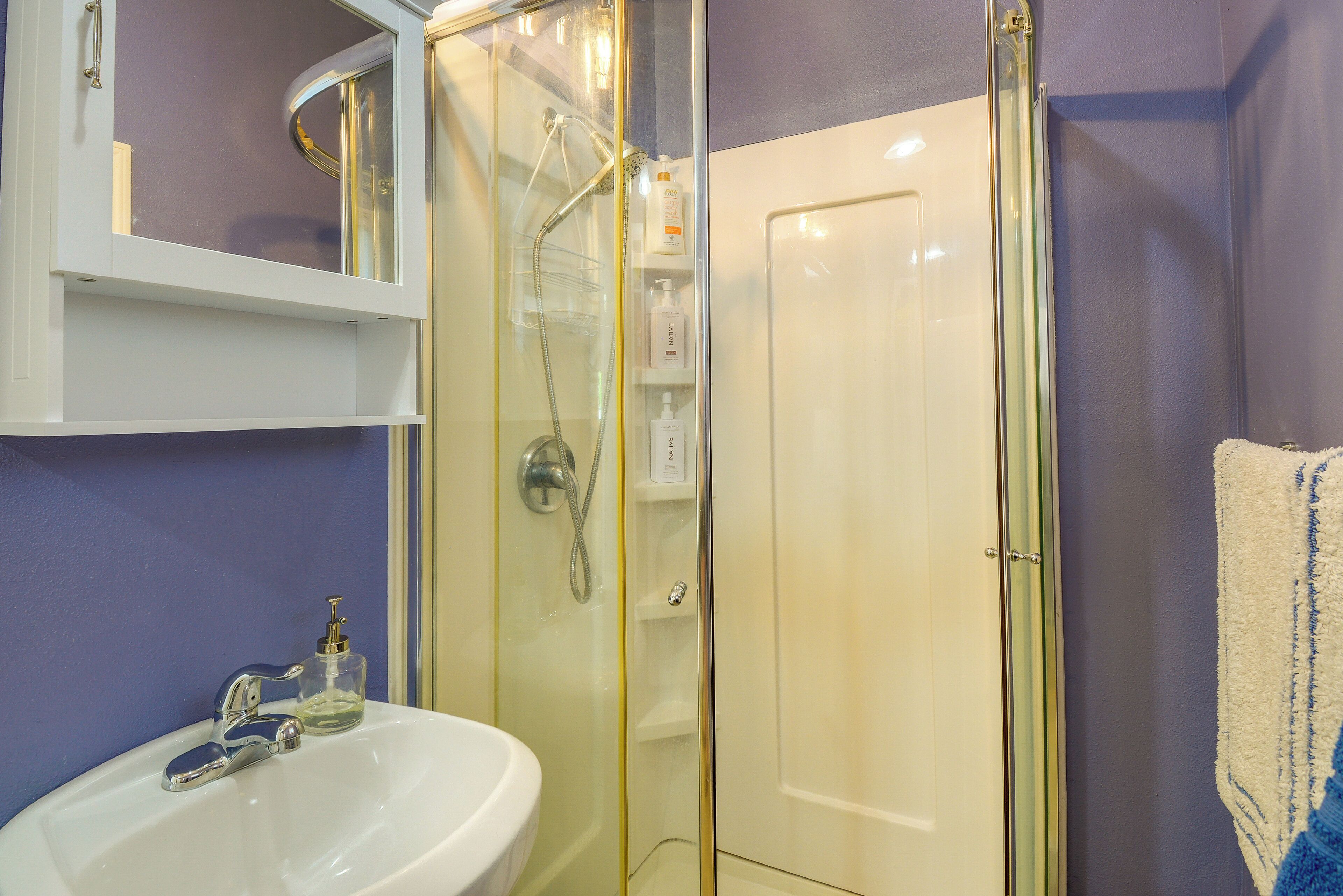 A bathroom with a glass-enclosed shower, a white sink, and a mirror above the sink.