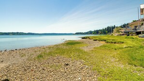 A lakeside property with a rocky shoreline, grassy areas, and a view of the lake. - Waterfront Hood Canal Cottage: Steps to the Beach! (Belfair)