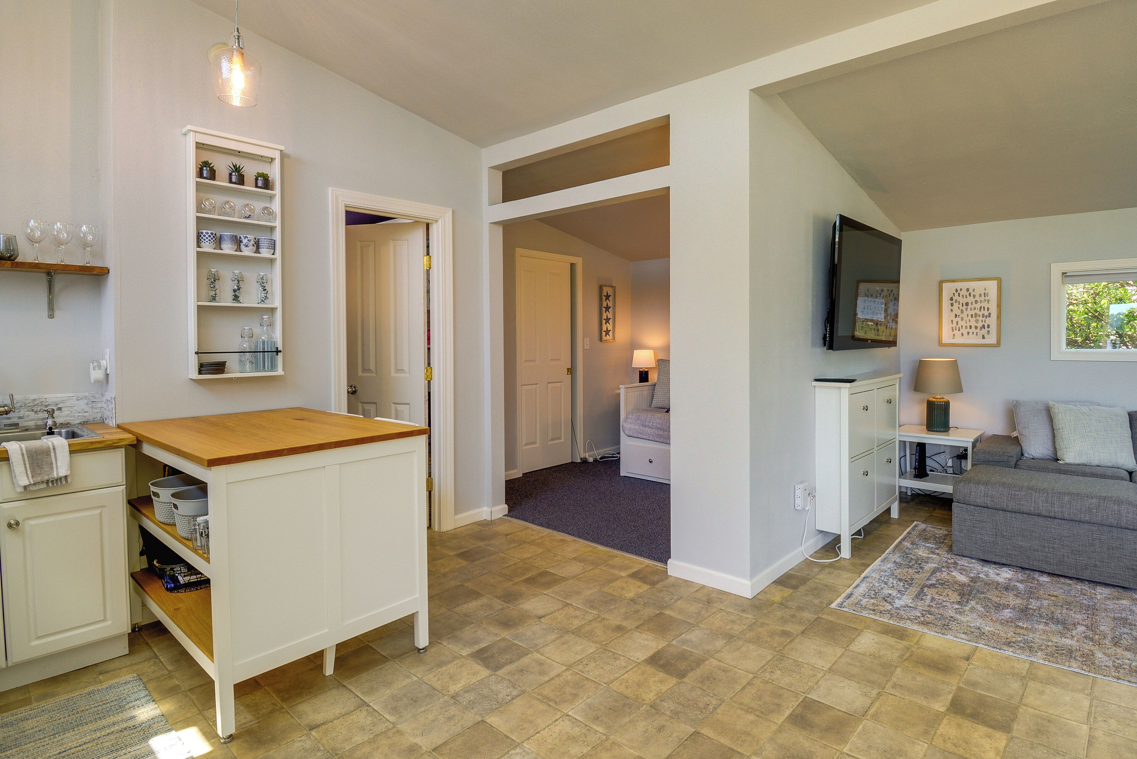A compact living space with a kitchen area, a dining table, a sofa, and a television.