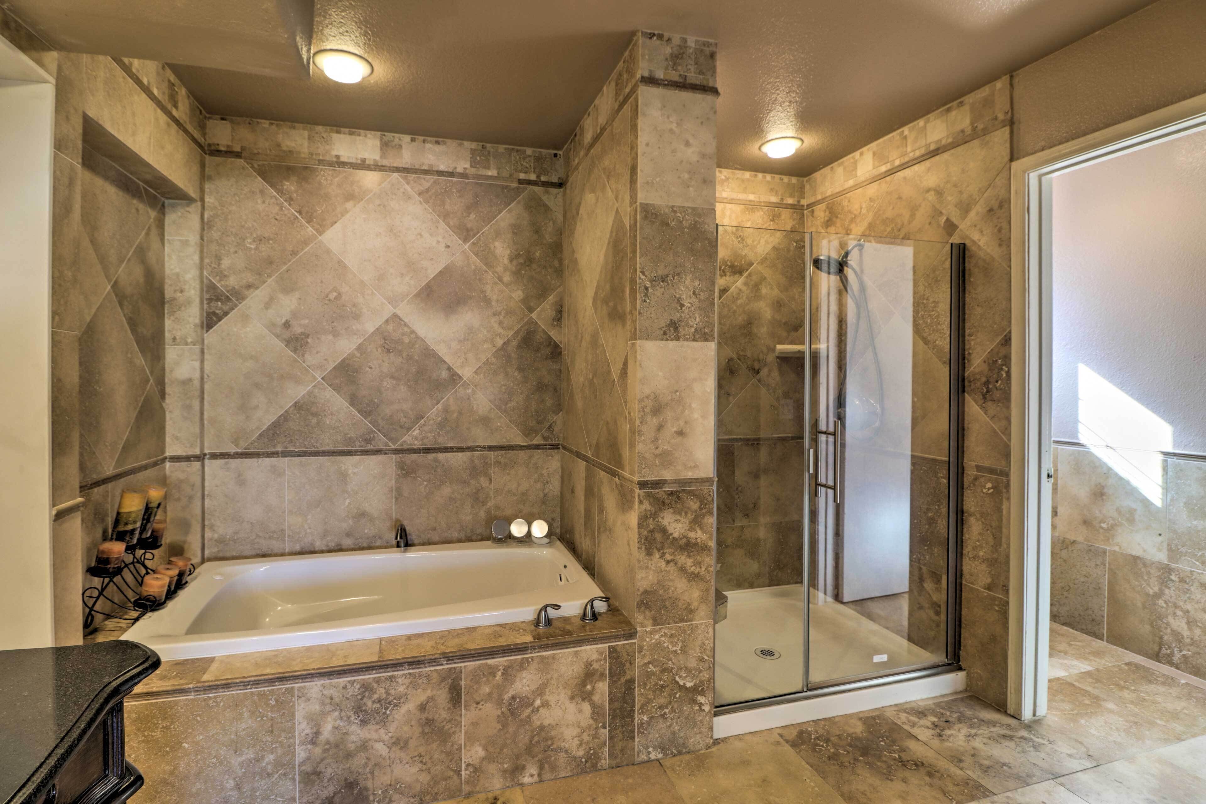 A modern bathroom with a freestanding bathtub, a glass-enclosed shower, and a tiled floor.