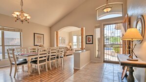 A spacious dining area with a wooden table and chairs, a chandelier, and a view through a glass door. - Hot Tub & Fire Pit: Mtn-view Mesa Home! (Mesa)