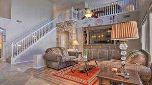 A spacious living area with a stone fireplace, a television, and a staircase leading to an upper level. - Hot Tub & Fire Pit: Mtn-view Mesa Home! (Mesa)